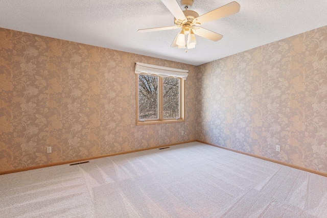 spare room featuring light carpet, visible vents, a textured ceiling, and ceiling fan