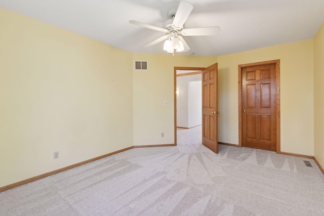 empty room with ceiling fan, light carpet, visible vents, and baseboards