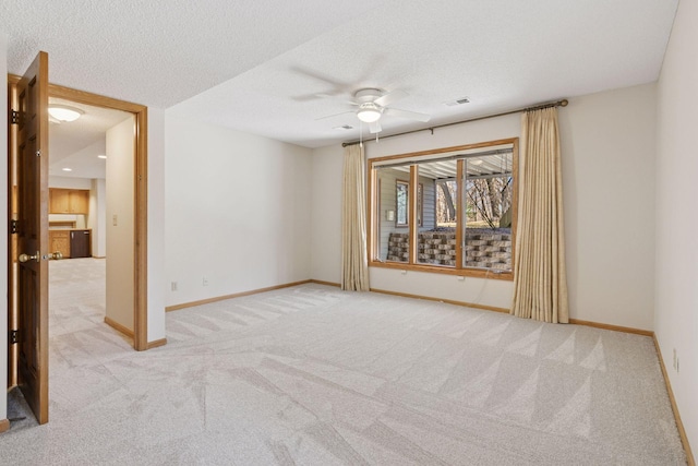 carpeted empty room with baseboards, visible vents, a textured ceiling, and ceiling fan