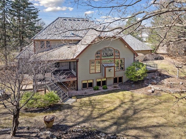 rear view of house featuring a yard, a deck, and stairs