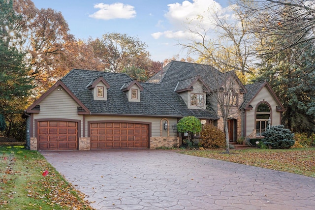 view of front of house with an attached garage, brick siding, and decorative driveway