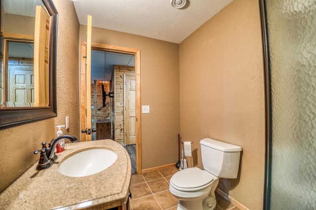 bathroom with tile patterned floors, vanity, toilet, and a textured ceiling