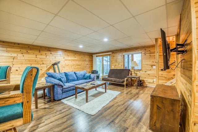 living room with wooden walls, hardwood / wood-style floors, and a drop ceiling