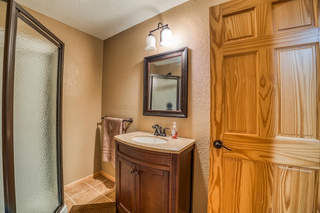 bathroom with tile patterned flooring, a textured ceiling, vanity, and a shower with shower door