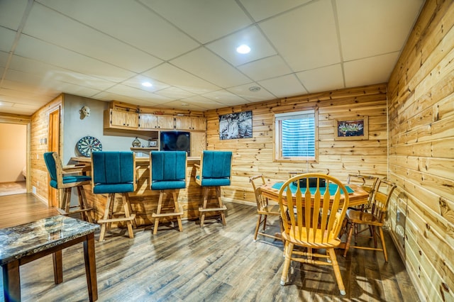 playroom with hardwood / wood-style floors, a drop ceiling, and wooden walls