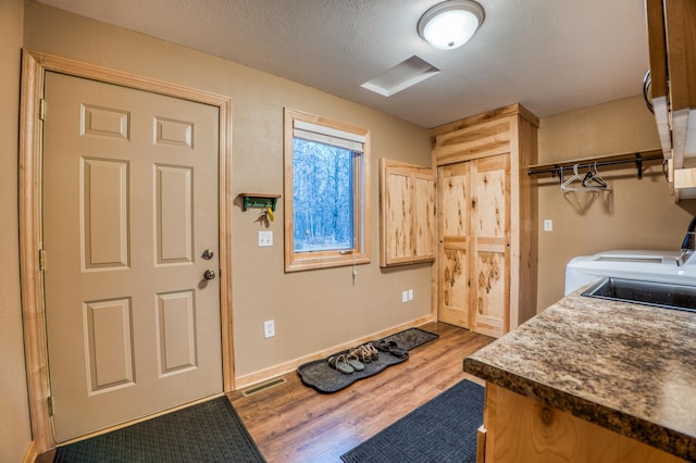 laundry room with sink, wood-type flooring, a textured ceiling, and washing machine and clothes dryer