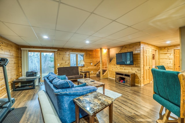 living room featuring wooden walls, hardwood / wood-style floors, and a drop ceiling