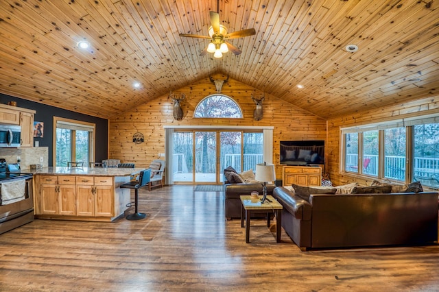 living room featuring ceiling fan, hardwood / wood-style floors, wood ceiling, and wood walls