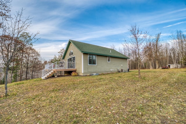 view of side of home with a lawn, cooling unit, and a deck