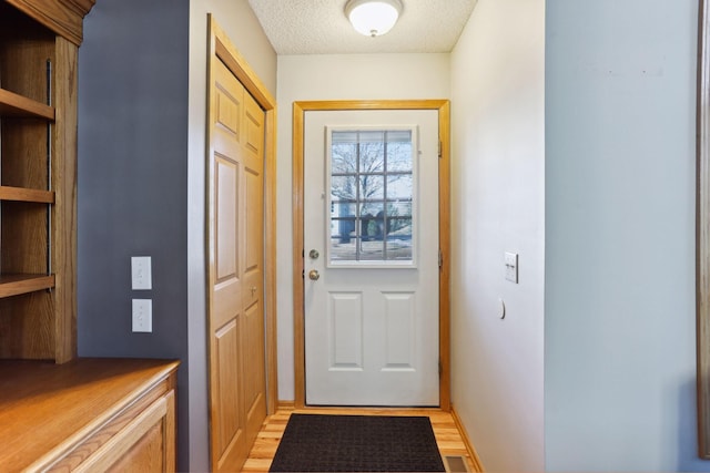 entryway featuring light wood-type flooring, a textured ceiling, and visible vents