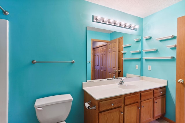 bathroom with vanity, toilet, and a textured ceiling