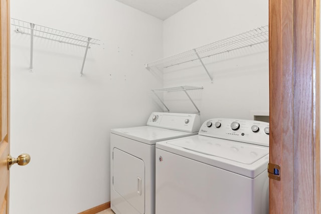 washroom featuring washing machine and clothes dryer, laundry area, and baseboards