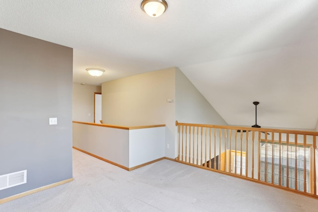 corridor featuring baseboards, visible vents, carpet floors, vaulted ceiling, and a textured ceiling