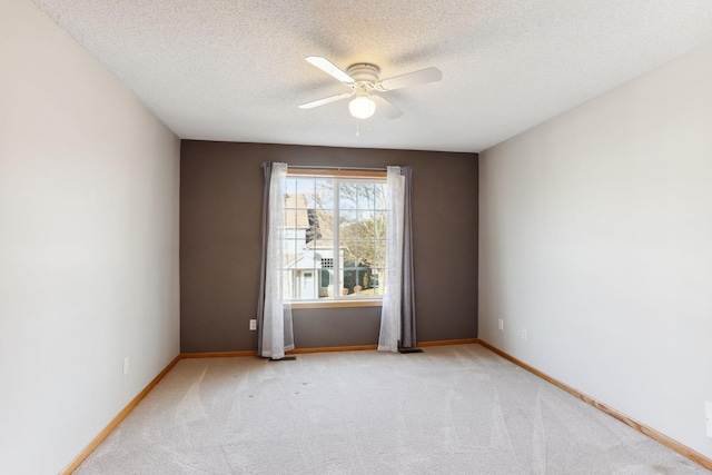 spare room with baseboards, light colored carpet, ceiling fan, and a textured ceiling