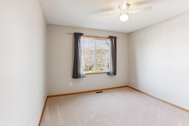 carpeted empty room with ceiling fan, visible vents, baseboards, and a textured ceiling