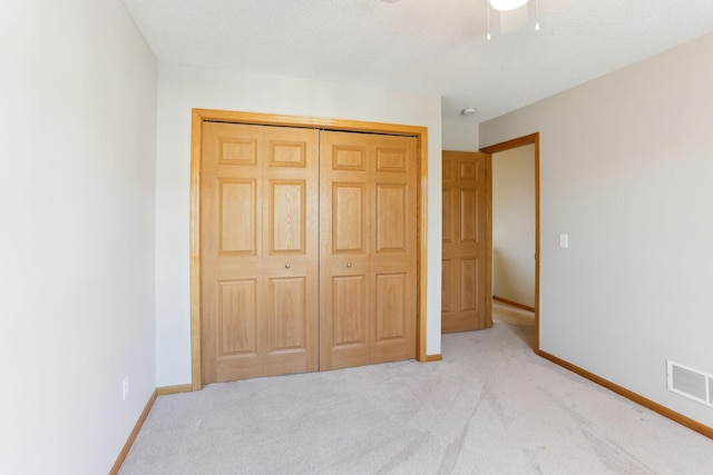 unfurnished bedroom with visible vents, a textured ceiling, a closet, carpet, and baseboards