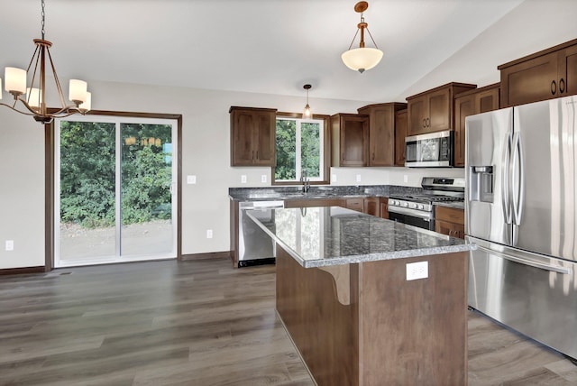 kitchen with appliances with stainless steel finishes, lofted ceiling, a kitchen island, and hanging light fixtures