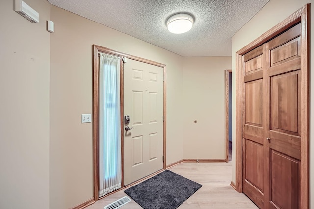 entrance foyer with light wood-type flooring and a textured ceiling