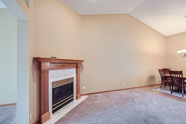 interior space featuring a tile fireplace, light carpet, and vaulted ceiling