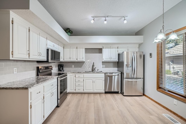 kitchen featuring white cabinets, appliances with stainless steel finishes, sink, and pendant lighting