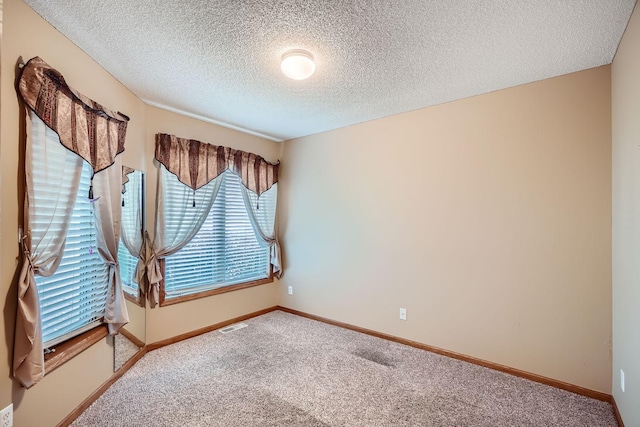 carpeted spare room with a textured ceiling