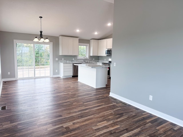 kitchen featuring a wealth of natural light, appliances with stainless steel finishes, hanging light fixtures, and white cabinetry