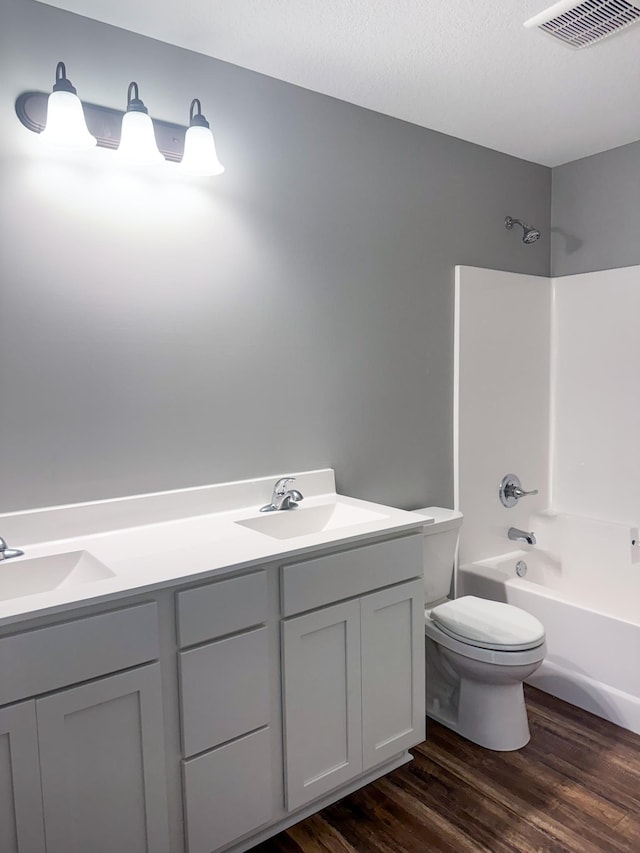 full bathroom with vanity, toilet, wood-type flooring, and washtub / shower combination