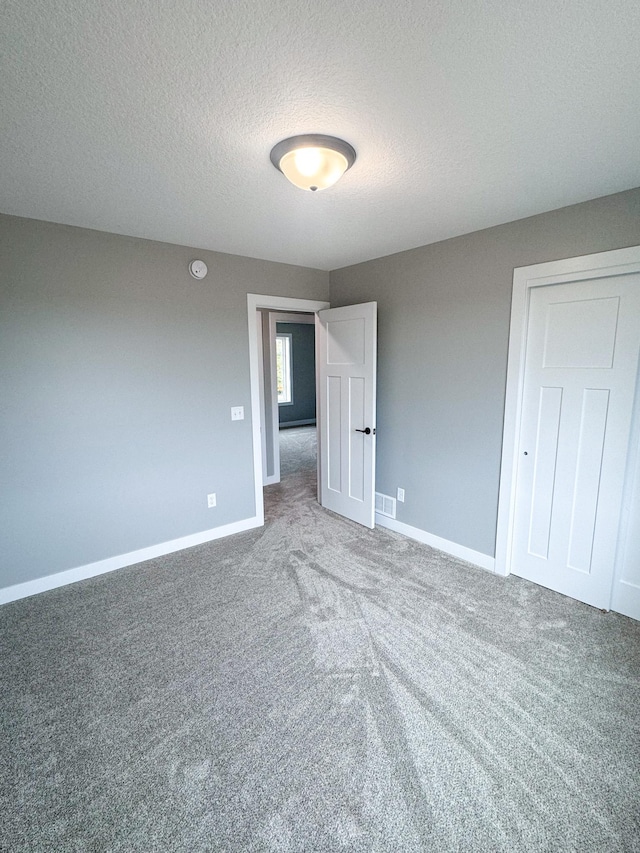 unfurnished bedroom with a textured ceiling, carpet flooring, and a closet