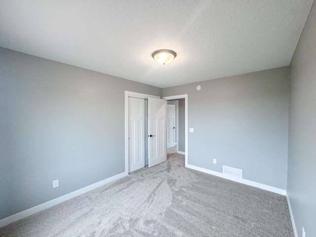 unfurnished bedroom with a textured ceiling, carpet floors, and a closet