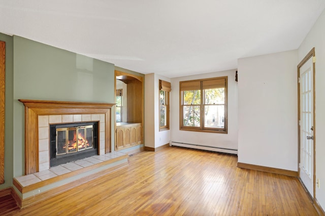 unfurnished living room with baseboard heating, a fireplace, and light wood-type flooring