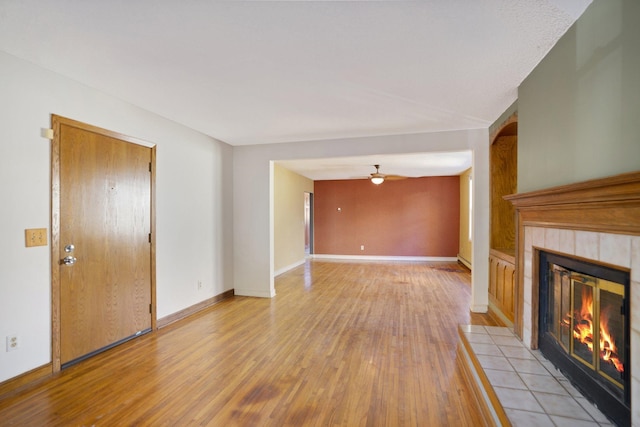 unfurnished living room featuring ceiling fan, light hardwood / wood-style flooring, and a fireplace