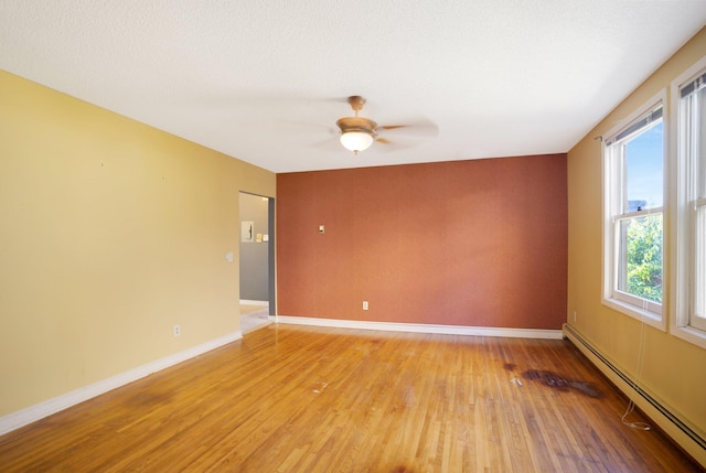 unfurnished room with ceiling fan, a textured ceiling, a baseboard heating unit, and light wood-type flooring