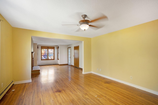 spare room featuring a textured ceiling, wood-type flooring, a baseboard radiator, and ceiling fan