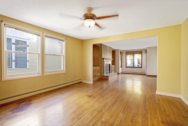 unfurnished living room with light hardwood / wood-style floors, a textured ceiling, a baseboard radiator, and ceiling fan