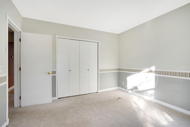 unfurnished bedroom featuring light carpet and a closet