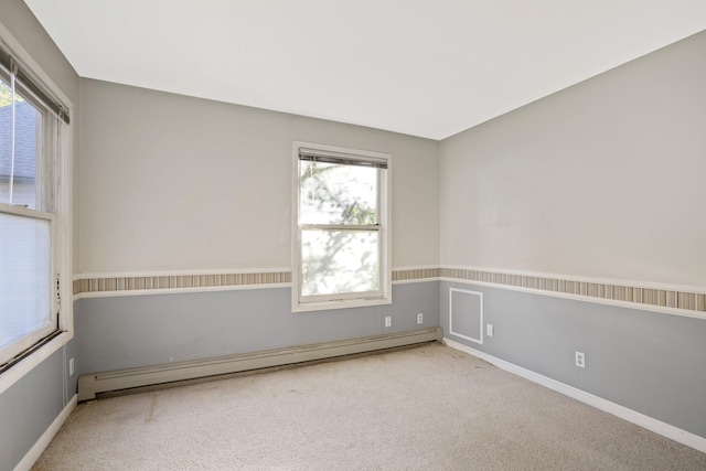 empty room with light carpet, baseboard heating, and plenty of natural light