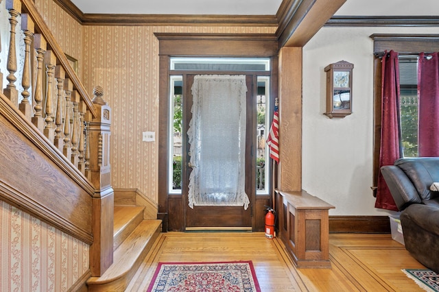 foyer featuring light hardwood / wood-style flooring, ornamental molding, and a healthy amount of sunlight