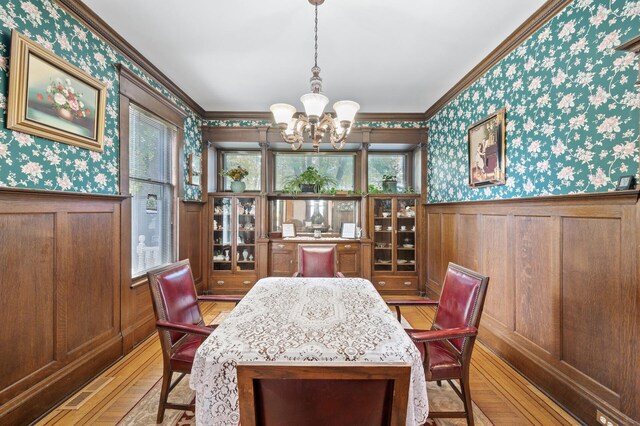 2523 Dupont Ave N, Minneapolis, MN 55411 - dining room with light wood-style floors, a wainscoted wall, wallpapered walls, ornamental molding, and a notable chandelier
