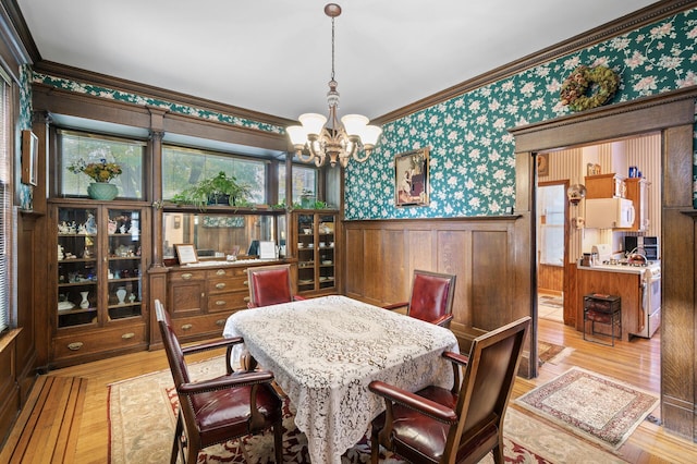 dining area with light hardwood / wood-style flooring, ornamental molding, and a notable chandelier