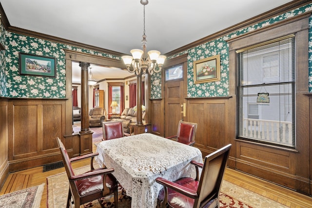 dining room featuring crown molding, a notable chandelier, light parquet floors, and decorative columns