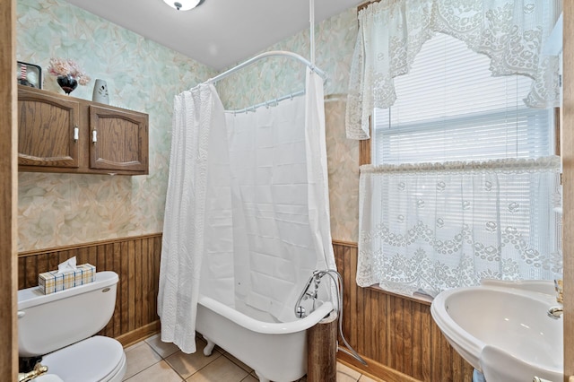 full bathroom featuring sink, toilet, shower / bath combo with shower curtain, wooden walls, and tile patterned flooring