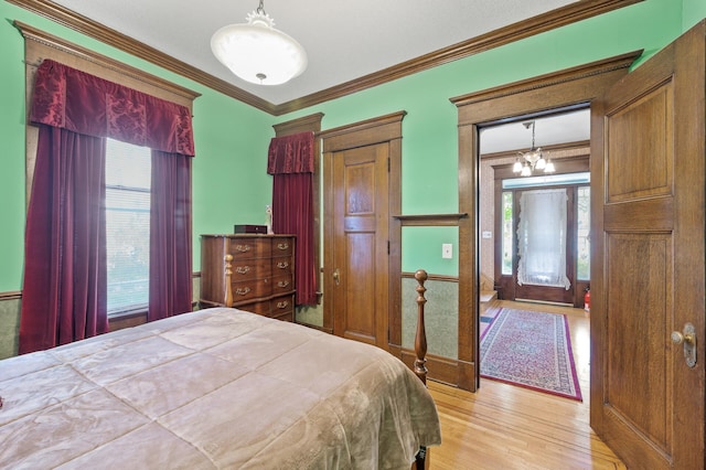 bedroom with light hardwood / wood-style flooring, ornamental molding, and a chandelier