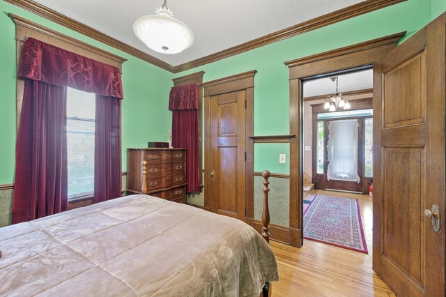 2523 Dupont Ave N, Minneapolis, MN 55411 - bedroom featuring wood finished floors, crown molding, and a notable chandelier