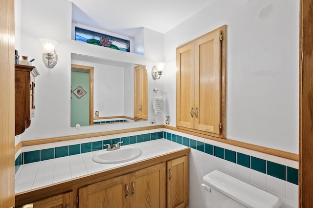 bathroom featuring toilet, vanity, and tile walls