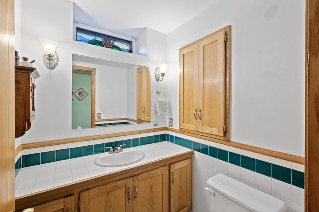 2523 Dupont Ave N, Minneapolis, MN 55411 - bathroom featuring vanity, toilet, a wainscoted wall, and tile walls