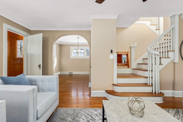 living area featuring stairs, ornamental molding, and wood finished floors