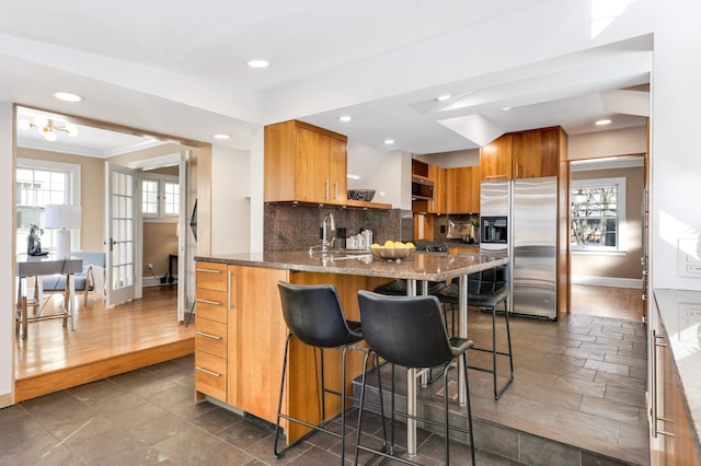 kitchen featuring tasteful backsplash, dark stone counters, appliances with stainless steel finishes, a kitchen bar, and open shelves