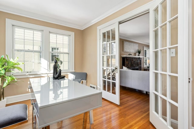 home office featuring a fireplace, ornamental molding, wood finished floors, and french doors