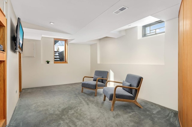 sitting room with lofted ceiling, visible vents, and dark carpet