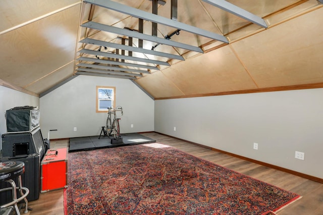 interior space featuring baseboards, vaulted ceiling, and wood finished floors